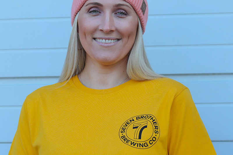 A Asmiling Woman Wearing A Seven Bro7Hers Manchester Yellow T Shirt